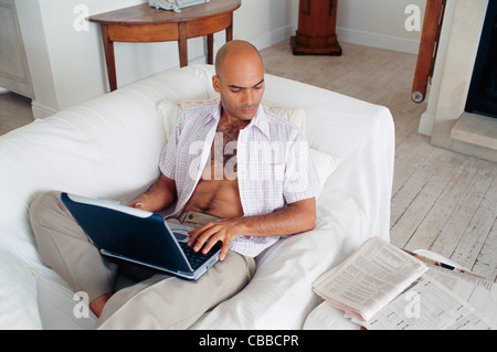 Man studying with laptop on couch Stock Photo