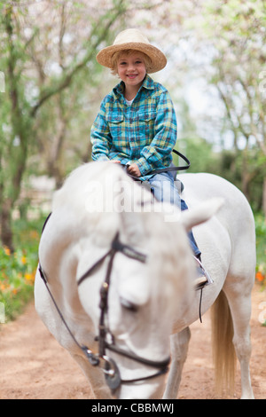 Smiling boy riding horse in park Stock Photo