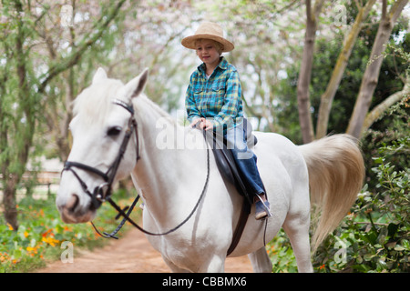 Smiling boy riding horse in park Stock Photo