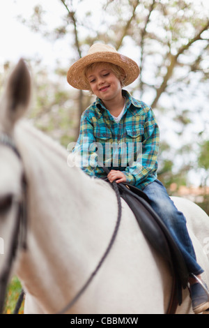 Smiling boy riding horse in park Stock Photo