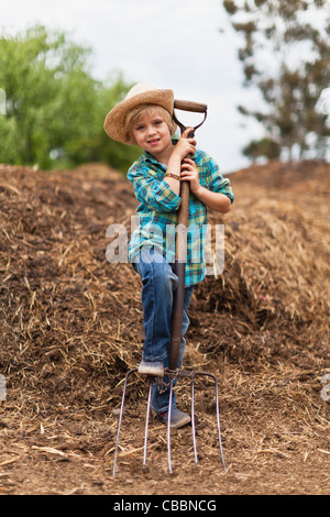 Boy using pitchfork in haystack Stock Photo
