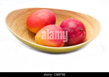 Close-up of fresh mangoes in a bamboo bowl on white background Stock Photo