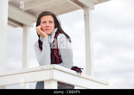 Thoughtful pretty woman leaning on fence looking away Stock Photo