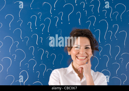 thinking business woman in front of question marks written blackboard Stock Photo