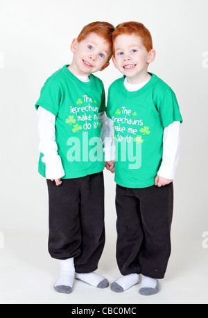 Smiling redheaded twins holding hands isolated on white Stock Photo