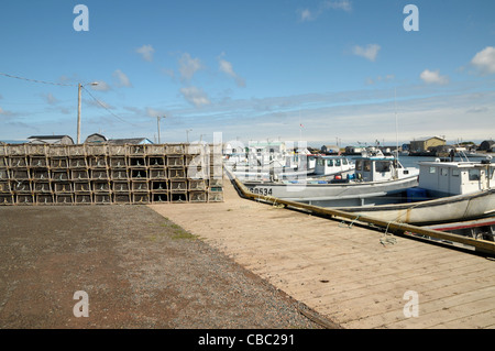 Lobster traps sit on the side as fishing boats are tied to the docks in the working harbor of North Lake Harbor, Prince Edward I Stock Photo