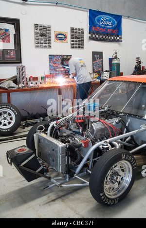 Drag racing enthusiast performing repairs to his Ford Mustang and welding in his workshop Stock Photo