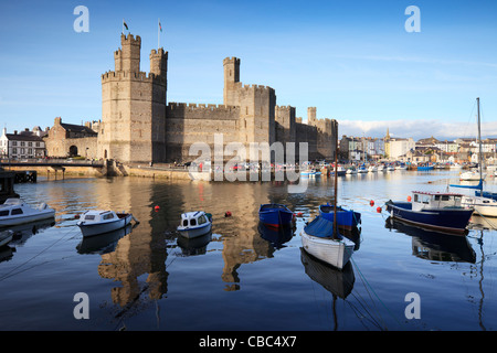 A bright summer evening at Caernarfon Castle, Gwynedd, North Wales. The castle is reflected in the River Seiont. Stock Photo