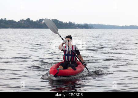 Woman kayaking on still lake Stock Photo