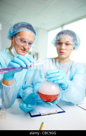 Laboratory workers mixing two chemical substances during laboratory experiment Stock Photo