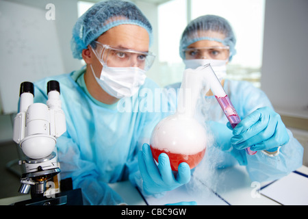 Laboratory workers compounding two chemical substances during laboratory experiment Stock Photo