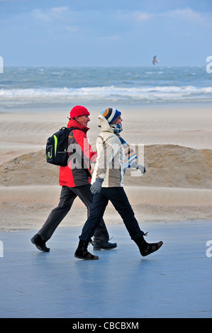 Couple walking in winter on sea dyke during stormy weather along the North Sea at Nieuwpoort, Belgium Stock Photo