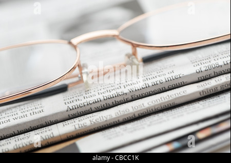 Eyeglasses lie on a pile of newspapers. A photo close up. Selective focus Stock Photo