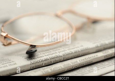 Eyeglasses lie on a pile of newspapers. A photo close up. Selective focus Stock Photo