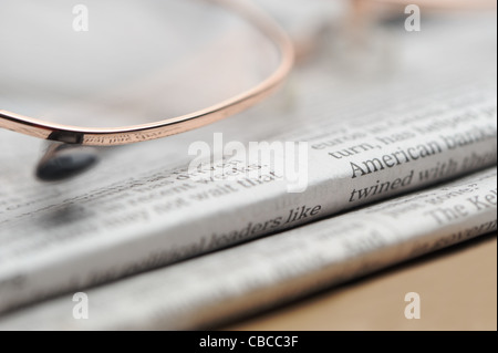 Eyeglasses lie on a pile of newspapers. A photo close up. Selective focus Stock Photo