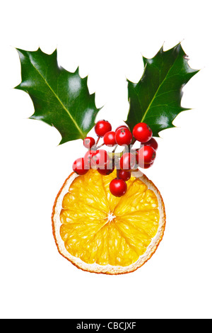 Photo of a Christmas decoration made with holly, red berries and a dried orange slice, isolated on a white background. Stock Photo