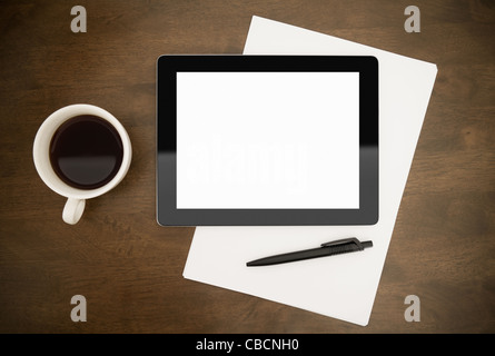 Contemporary digital tablet with blank screen lying on worktable with paper, pen and cup of coffee. Top directly above view. Stock Photo