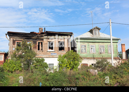 Two wooden houses in Russian province town. One of this after fire burning. Stock Photo