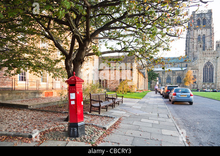 Sightseeing: Unusual old fashioned historic hexagonal red Victorian pillar box on Durham Cathedral Square with the cathedral in the background Stock Photo