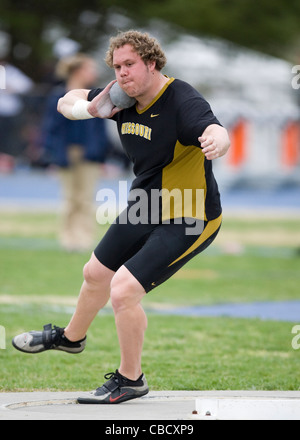 A male athlete throws a shot put during a track and field meet Stock Photo