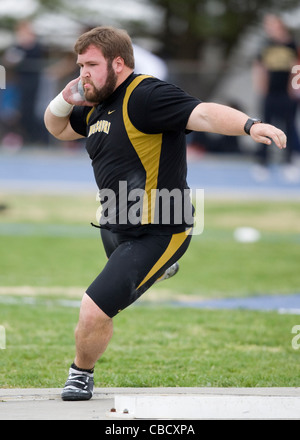 A male athlete throws a shot put during a track and field meet Stock Photo