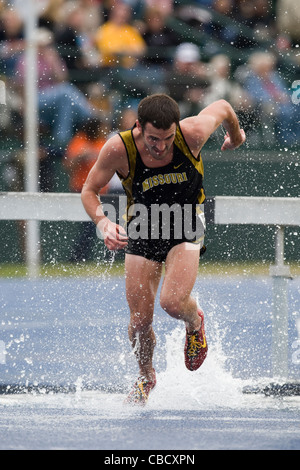 A male runner falls into the water hazard during a steeplechase race Stock Photo