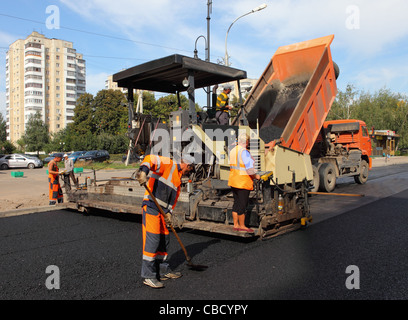 Road construction crew apply the first layer of asphalt on a paving project Stock Photo