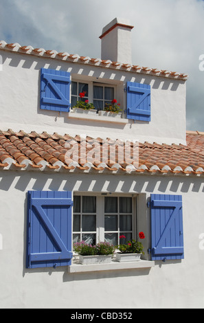 Typical tradtional island home with blue window shutters,, white washed walls, and red clay tiles on Noirmoutier island in Vendée Stock Photo