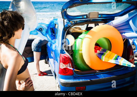 Woman unloading beach toys from car Stock Photo