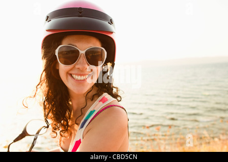 Smiling woman riding scooter on beach Stock Photo