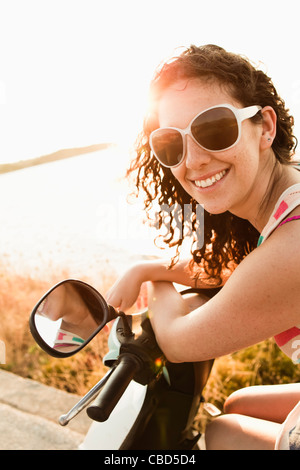 Smiling women riding scooter Stock Photo