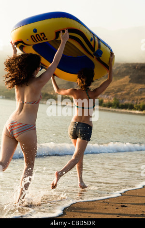 Women carrying inflatable boat on beach Stock Photo