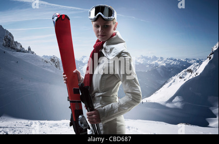 Woman carrying skis on snowy mountain Stock Photo
