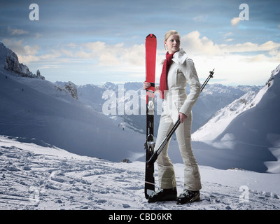 Woman carrying skis on snowy slope Stock Photo
