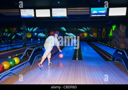 A woman ten pin bowling showing movement at Center Parcs in Elveden near Thetford , England , Britain , Uk Stock Photo