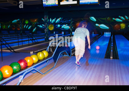 A woman ten pin bowling showing movement at Center Parcs in Elveden near Thetford , England , Britain , Uk Stock Photo