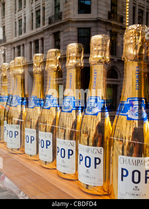 Gold coloured bottles of Champagne Pop for sale in the window of a shop in the City of London financial district England UK Stock Photo