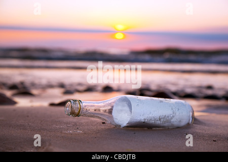 Message in a bottle by the sea on the beach at sunset Stock Photo
