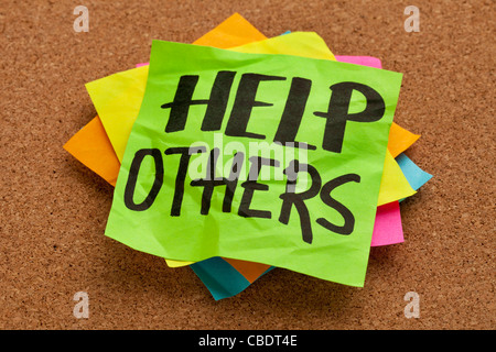 help others reminder on sticky note posted on a cork board Stock Photo