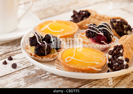 plate of fruit mini tarts and coffee on a rustic wooden table Stock Photo