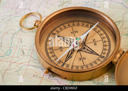 vintage pocket brass compass opened over topographical map Stock Photo