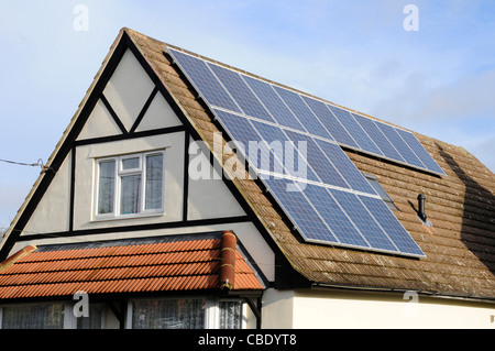 Solar Panels installed on roof of detached house alongside an existing rooflight Stock Photo