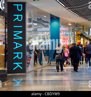 Close up of blue Primark shop front store sign & shopper people walking Westfield shopping centre mall at Stratford City Newham East London England UK Stock Photo