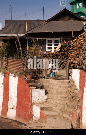 India, Nagaland, T Khel, Old Kohima Village boy at house gate beside pile of firewood Stock Photo