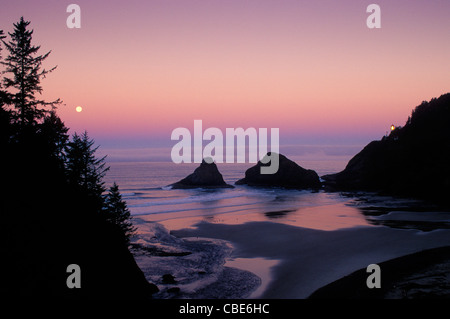 Heceta Head Lighthouse and full moon setting over ocean; Devils Elbow State Park, Oregon coast. Stock Photo