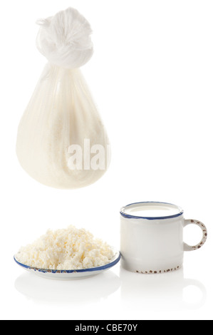 Cottage cheese and milk. Fresh organic handmade cheese hanging in cheesecloth, milk and vintage plate Stock Photo