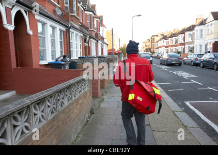 postman delivering mail on a cold december morning in cricklewood north london england united kingdom uk Stock Photo