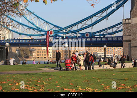Tourists walking along the Queen's Walk by Tower Bridge over the River Thames in London, England, UK, in Autumn Stock Photo