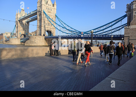 Tourists walking along Queen's Walk by Tower Bridge over the River Thames in London, England, UK, in Autumn Stock Photo