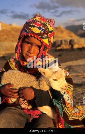 Sachsayhuaman, Peru. Boy in traditional dress holding a young llama 'cria'. Stock Photo